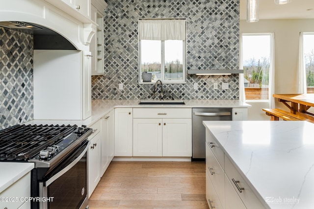 3030 E Sandman Cir, Wasilla, AK 99654 - kitchen featuring a sink, appliances with stainless steel finishes, backsplash, light wood-type flooring, and white cabinetry