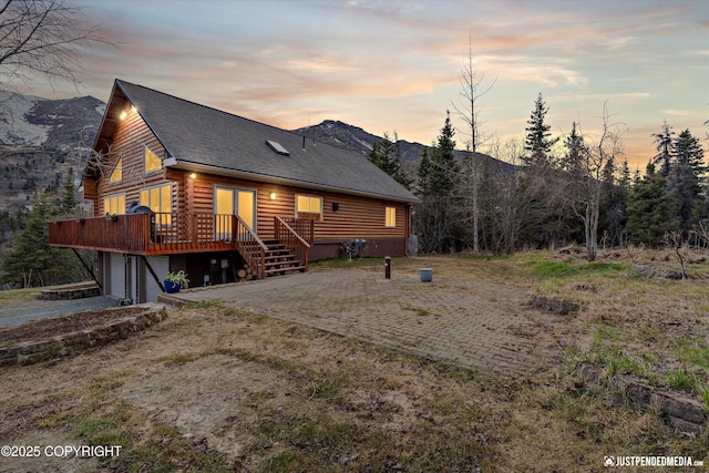 3915 Hiland Rd, Eagle River, AK 99577 - back of property with log exterior, a wooden deck, a garage, driveway, and roof with shingles