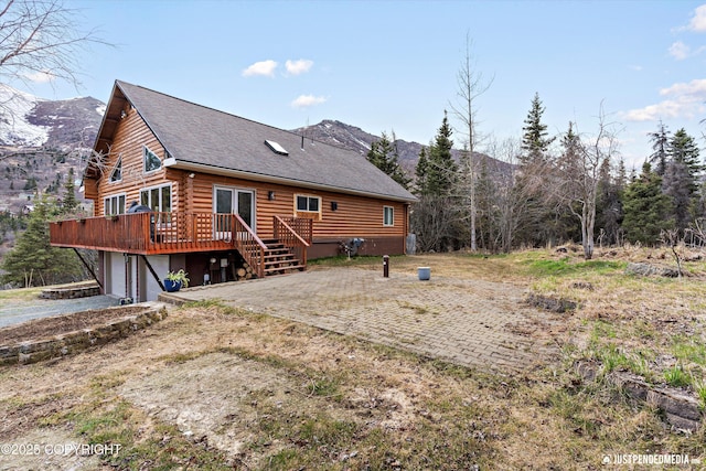 3915 Hiland Rd, Eagle River, AK 99577 - rear view of house featuring a deck with mountain view, log exterior, an attached garage, and roof with shingles