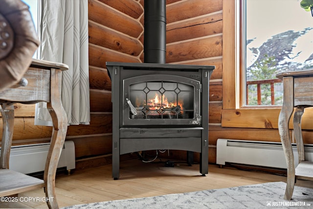 3915 Hiland Rd, Eagle River, AK 99577 - detailed view of log walls, wood finished floors, baseboard heating, a wood stove, and a baseboard radiator
