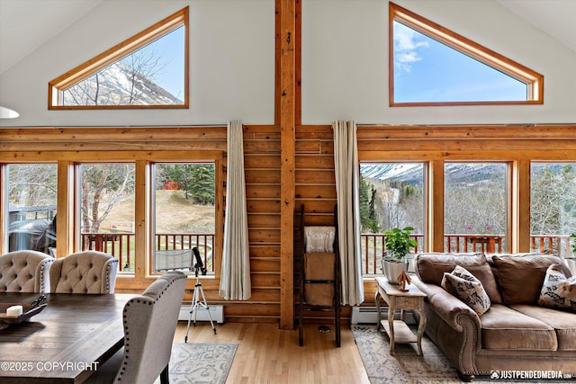 3915 Hiland Rd, Eagle River, AK 99577 - living area with log walls, a towering ceiling, hardwood / wood-style floors, and baseboard heating
