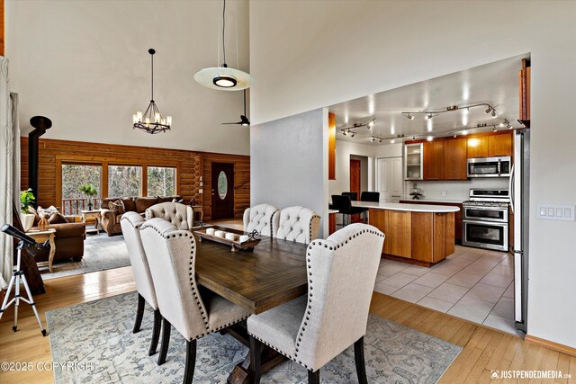 3915 Hiland Rd, Eagle River, AK 99577 - dining room with a high ceiling, light wood-style flooring, a chandelier, track lighting, and a wood stove