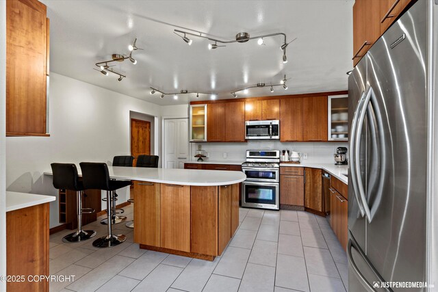3915 Hiland Rd, Eagle River, AK 99577 - kitchen with appliances with stainless steel finishes, brown cabinetry, glass insert cabinets, light countertops, and a peninsula
