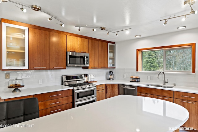 3915 Hiland Rd, Eagle River, AK 99577 - kitchen with stainless steel appliances, a sink, brown cabinetry, and rail lighting