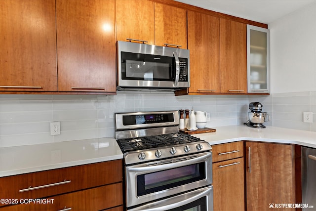 3915 Hiland Rd, Eagle River, AK 99577 - kitchen with stainless steel appliances, decorative backsplash, light countertops, brown cabinets, and glass insert cabinets