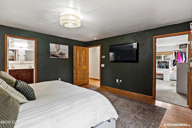 3915 Hiland Rd, Eagle River, AK 99577 - bedroom with wood finished floors, a walk in closet, baseboards, connected bathroom, and a closet