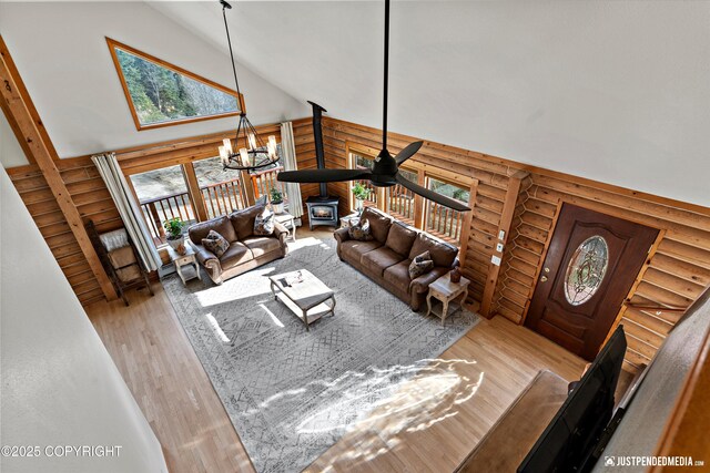 3915 Hiland Rd, Eagle River, AK 99577 - living area featuring high vaulted ceiling, rustic walls, a wood stove, wood finished floors, and a chandelier