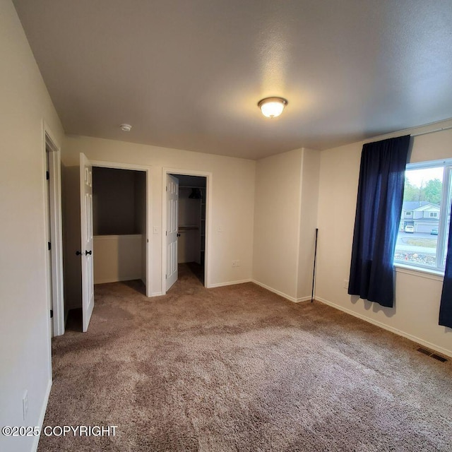 unfurnished bedroom featuring baseboards, carpet flooring, and visible vents