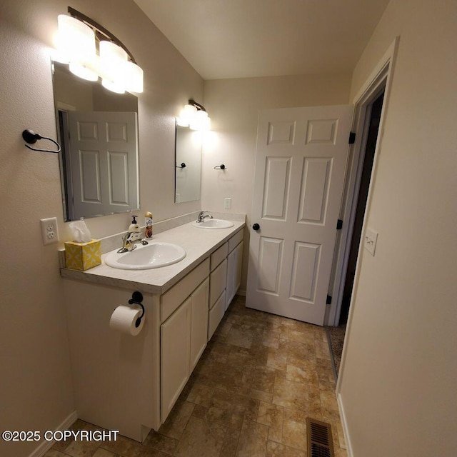 bathroom featuring stone finish flooring, baseboards, visible vents, and a sink