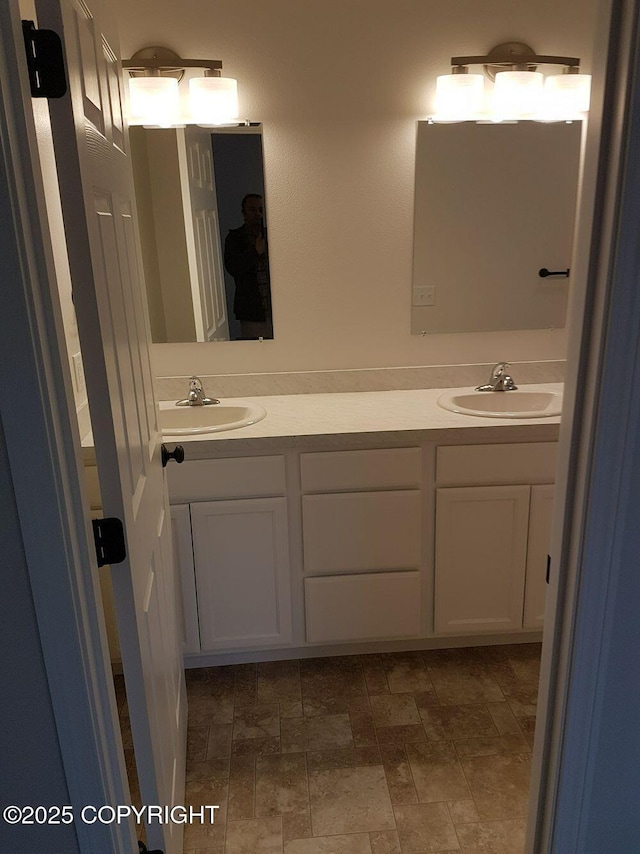 bathroom with a sink, stone finish floor, and double vanity