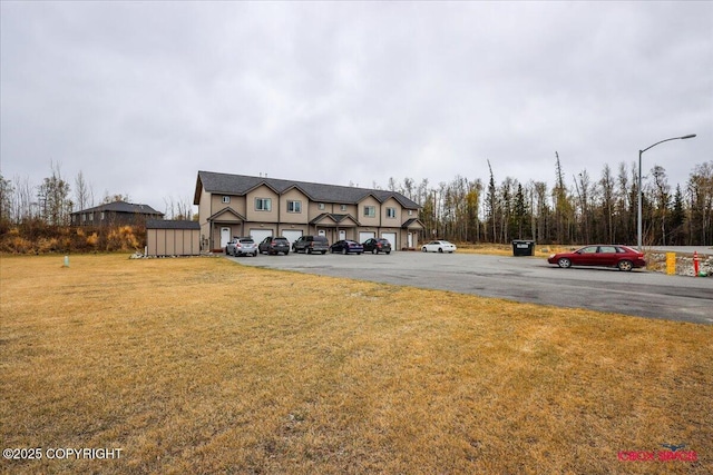 view of front of home with uncovered parking and a front lawn
