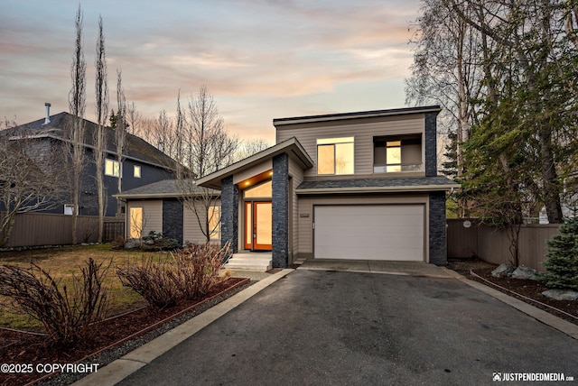 view of front of house with fence, a garage, and aphalt driveway