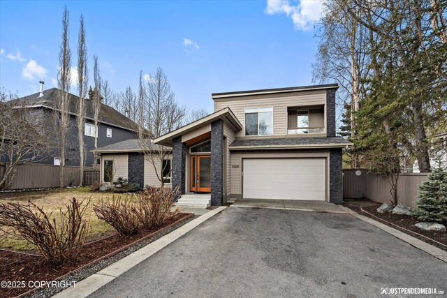 mid-century inspired home with a garage, fence, and aphalt driveway