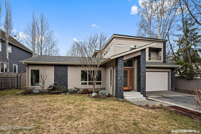 mid-century modern home with a garage, fence, driveway, and a front yard