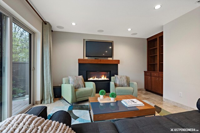 living area with recessed lighting, a glass covered fireplace, and radiator