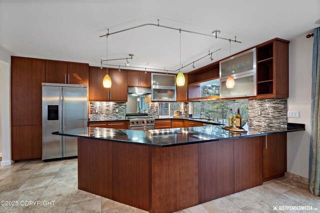kitchen with decorative light fixtures, open shelves, a peninsula, premium appliances, and under cabinet range hood