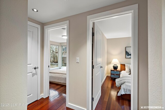 corridor featuring dark wood-type flooring and baseboards