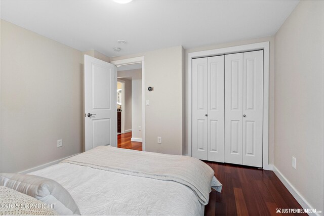 bedroom with baseboards, dark wood finished floors, and a closet