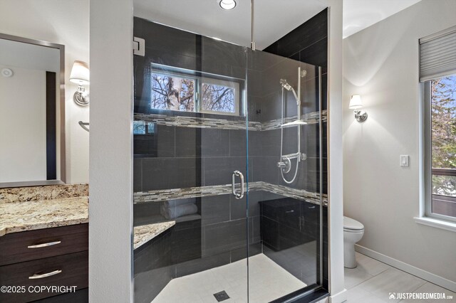 bathroom with tile patterned flooring, vanity, toilet, baseboards, and a stall shower