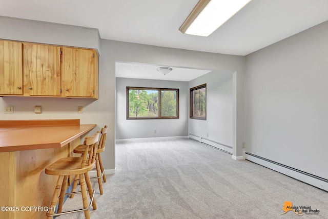3211 Shamrock St, Anchorage, AK 99504 - kitchen with baseboard heating, light carpet, a breakfast bar area, and light countertops