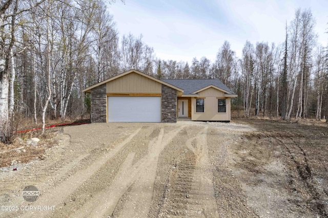 7177 N Paw St, Wasilla, AK 99654 - ranch-style home featuring a garage, dirt driveway, a shingled roof, and stone siding