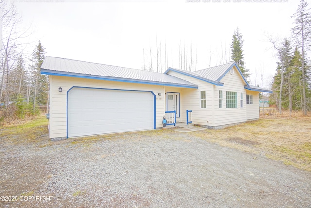 ranch-style home with dirt driveway, metal roof, and a garage