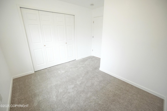unfurnished bedroom featuring carpet floors, baseboards, and a closet