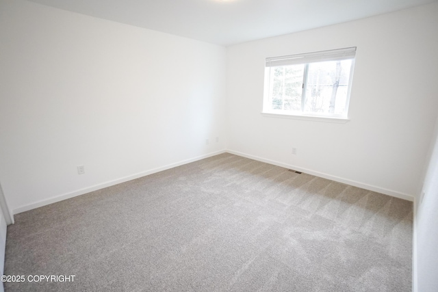 carpeted empty room featuring baseboards and visible vents
