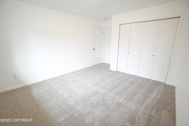 unfurnished bedroom with carpet flooring, baseboards, and a closet