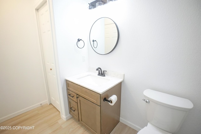 bathroom with vanity, baseboards, toilet, and wood finished floors