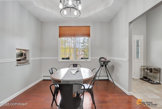 3541 E Wanamingo Dr, Wasilla, AK 99654 - dining space featuring a tray ceiling, a baseboard heating unit, baseboards, an inviting chandelier, and wood finished floors