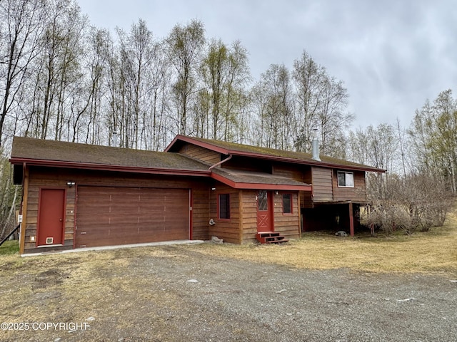 view of front of property featuring a garage, dirt driveway, and entry steps