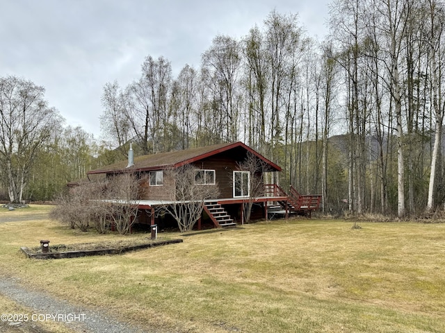 rear view of house with stairs, a wooden deck, a yard, and a wooded view