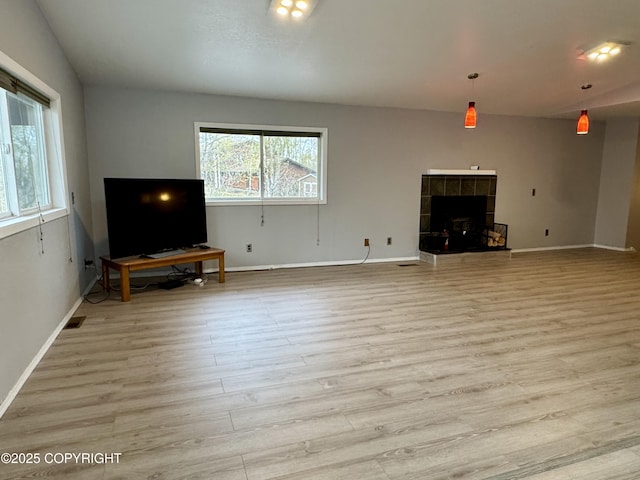 unfurnished living room featuring baseboards, light wood finished floors, visible vents, and a tile fireplace
