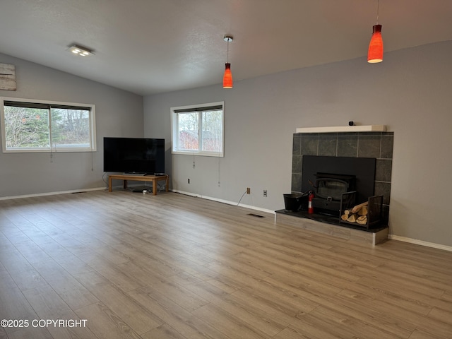 unfurnished living room featuring baseboards, a wealth of natural light, and a wood stove
