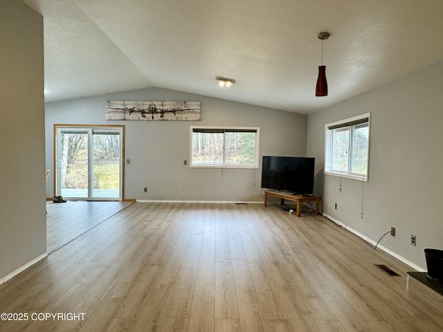 unfurnished living room featuring visible vents, lofted ceiling, wood finished floors, and a wealth of natural light