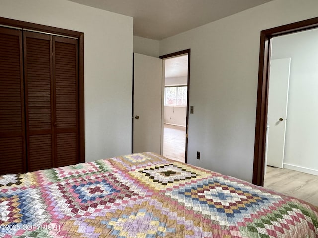 bedroom with baseboards, wood finished floors, and a closet