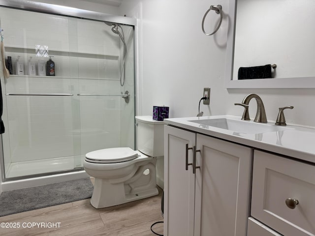 full bathroom with wood finished floors, a stall shower, toilet, and vanity