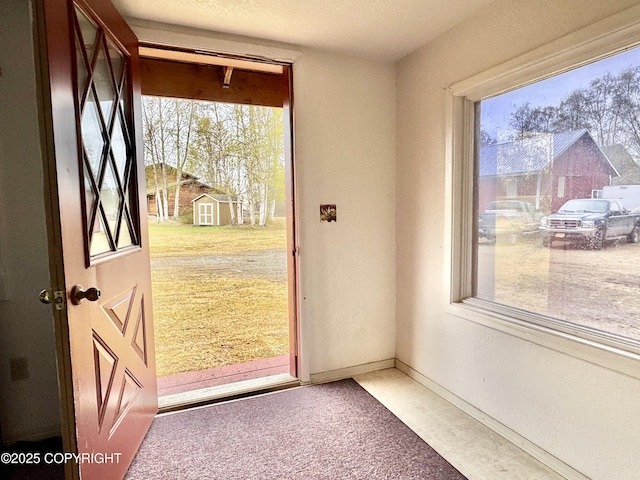doorway featuring baseboards and carpet
