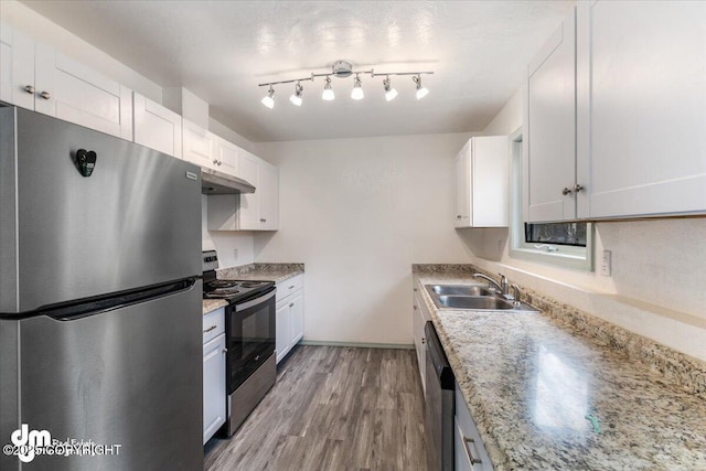 2601 E Quiet Cir, Wasilla, AK 99654 - kitchen with wood finished floors, white cabinetry, under cabinet range hood, a sink, and appliances with stainless steel finishes