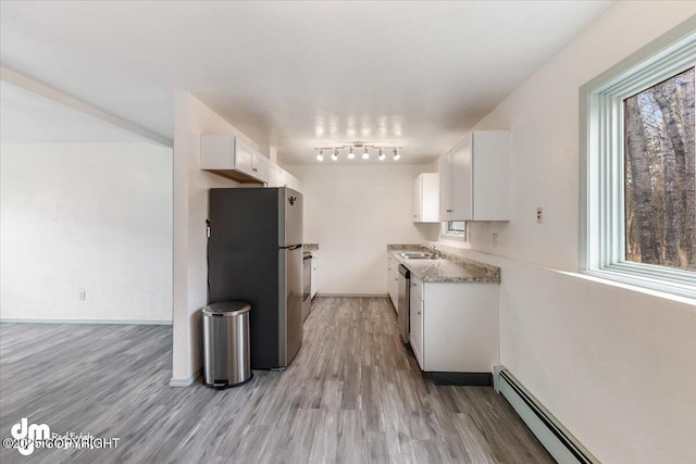 2601 E Quiet Cir, Wasilla, AK 99654 - kitchen with a baseboard radiator, white cabinets, a sink, light wood-style flooring, and appliances with stainless steel finishes