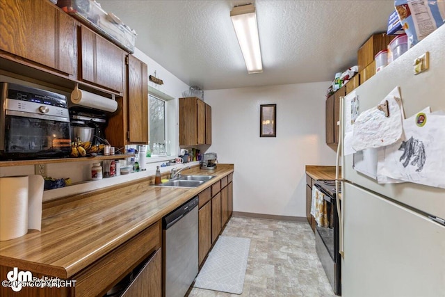 2601 E Quiet Cir, Wasilla, AK 99654 - kitchen with stainless steel dishwasher, freestanding refrigerator, black range with electric cooktop, baseboards, and a sink