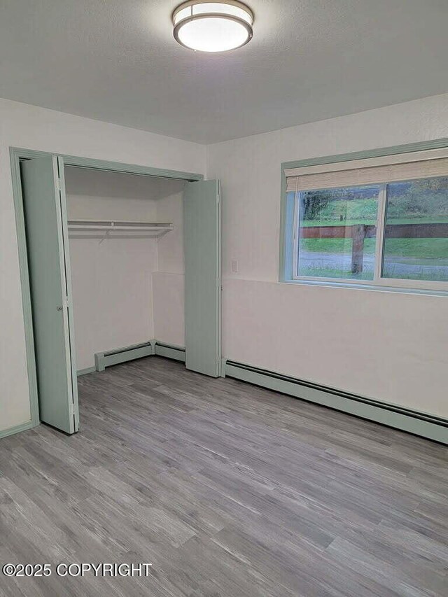 2601 E Quiet Cir, Wasilla, AK 99654 - unfurnished bedroom with a closet, a baseboard radiator, light wood-style floors, and a baseboard heating unit