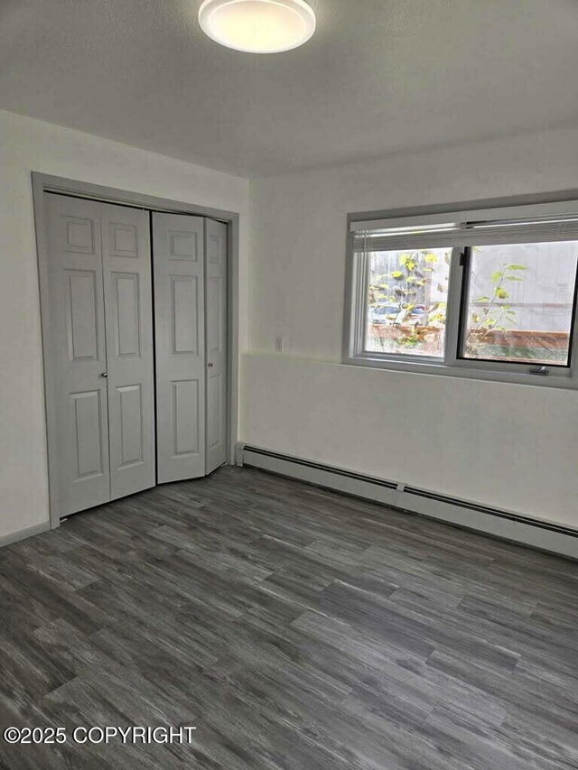 2601 E Quiet Cir, Wasilla, AK 99654 - unfurnished bedroom with a closet, wood finished floors, and a baseboard radiator