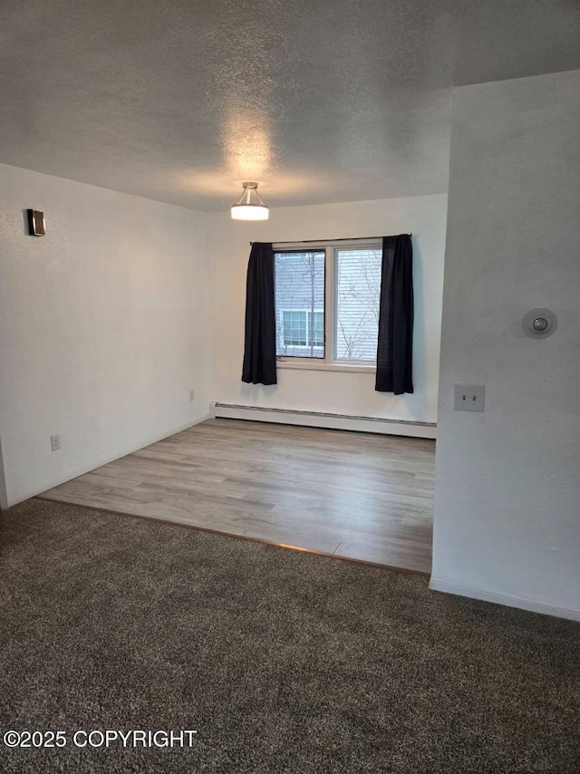 2601 E Quiet Cir, Wasilla, AK 99654 - empty room featuring carpet floors, baseboard heating, a textured ceiling, and wood finished floors