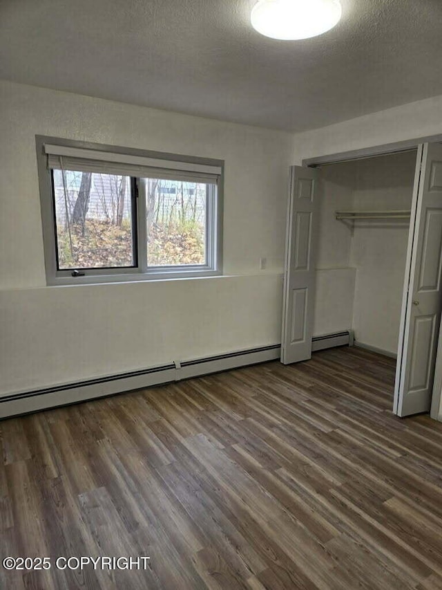 2601 E Quiet Cir, Wasilla, AK 99654 - unfurnished bedroom featuring baseboard heating, a closet, dark wood-style floors, and a textured ceiling