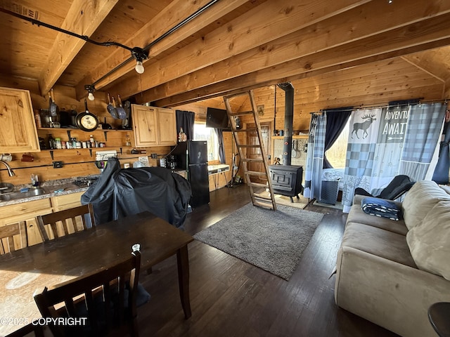 living room featuring wooden walls, dark wood finished floors, a wood stove, and wood ceiling with exposed beams