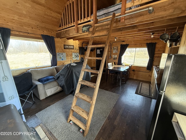 bedroom with freestanding refrigerator, wooden walls, lofted ceiling, and hardwood / wood-style floors