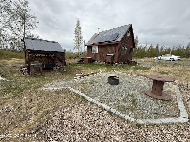 view of side of home featuring metal roof and an outbuilding