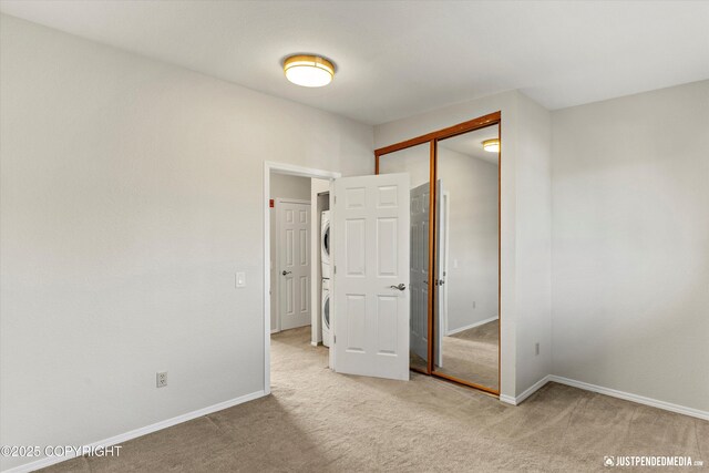 355 Donna Dr # 18, Anchorage, AK 99504 - unfurnished bedroom featuring stacked washer / drying machine, a closet, carpet floors, and baseboards